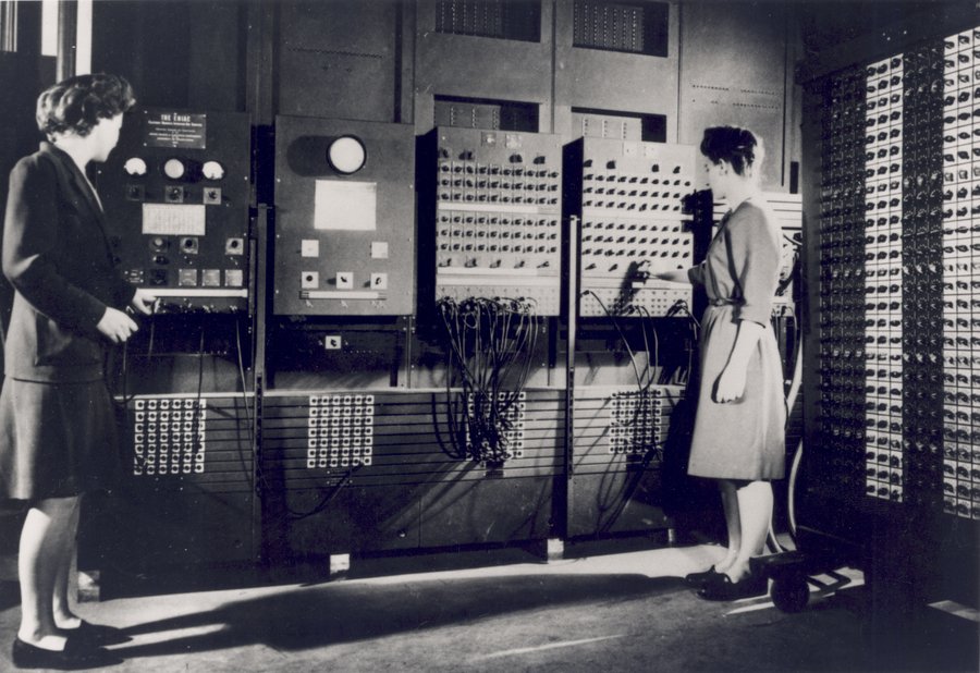 Two women operating the ENIAC, adjusting cables and switches on the machine panels, 1946